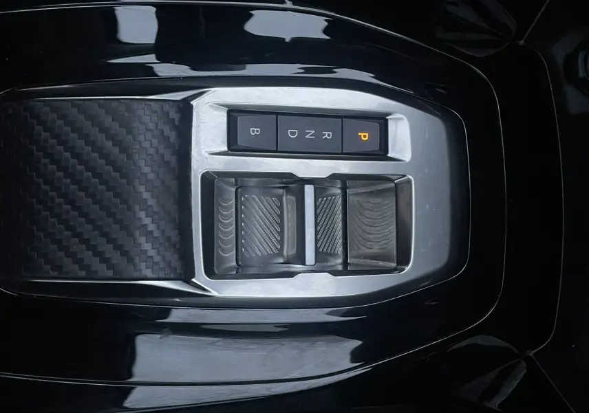 Gros plan sur la console centrale noire de la Peugeot 208 II électrique 2023 avec commandes de boîte automatique et finition carbone.