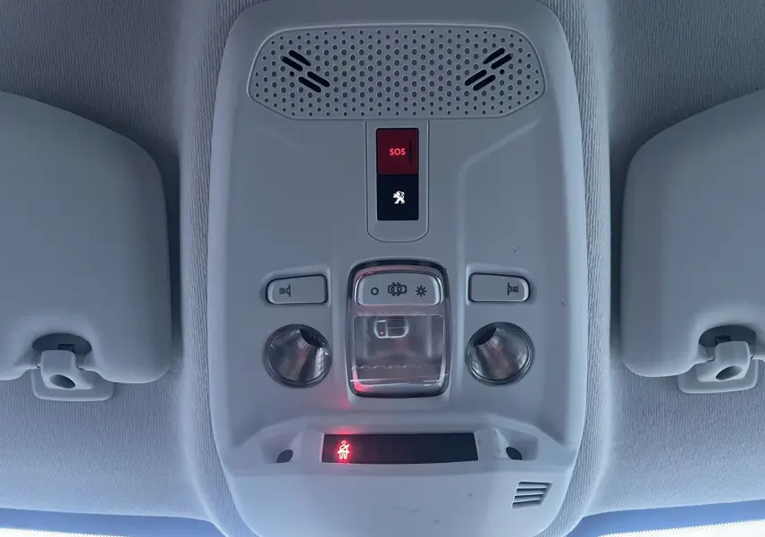 Plafonnier intérieur gris avec boutons SOS et éclairage, vu de dessous dans une Peugeot 208 électrique jaune 2023.