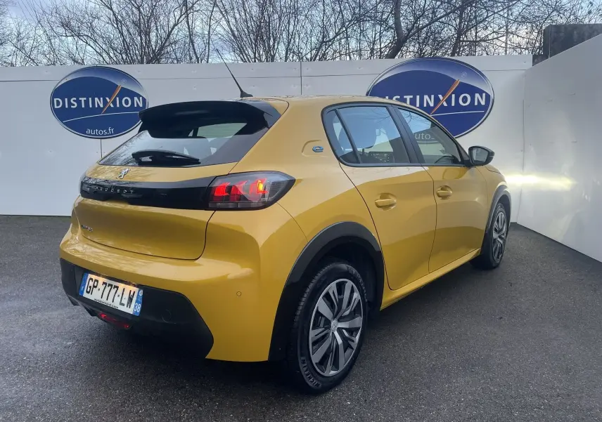 Peugeot 208 électrique jaune vue 3/4 arrière droit, avec feux arrière allumés et jantes spécifiques Active Pack.