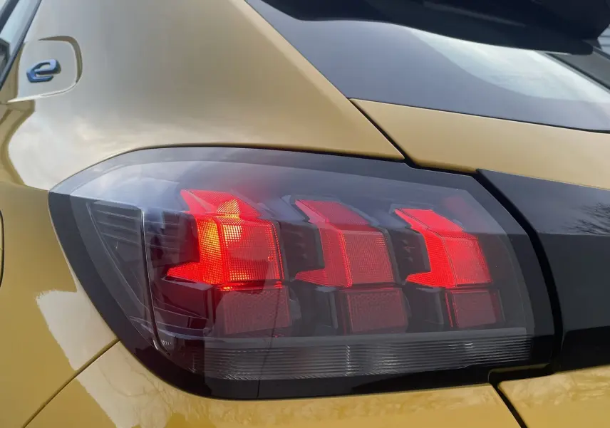 Gros plan sur le feu arrière gauche rouge d'une Peugeot 208 II électrique jaune 2023, mettant en valeur son design moderne.