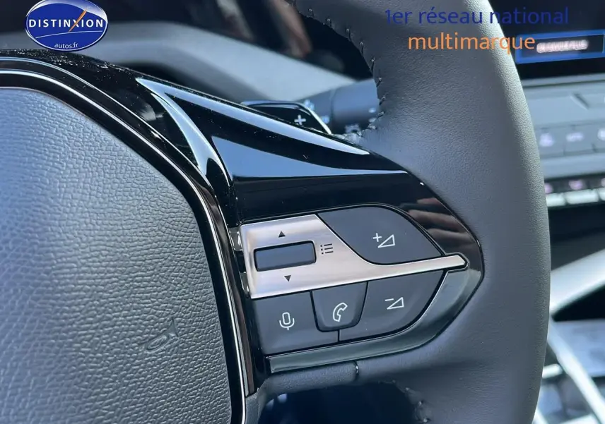 Gros plan sur les commandes multifonctions du volant cuir noir de la Peugeot 308 SW 2025 finition Allure.