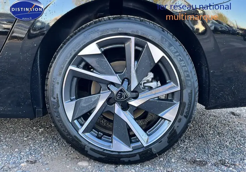Gros plan sur la jante alu avant droite de la Peugeot 308 SW noire perle avec logo lion central visible.