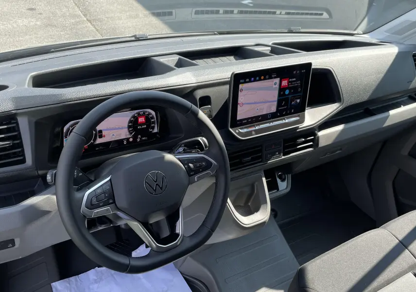Vue intérieure du tableau de bord du Volkswagen Crafter gris Indium, avec écran tactile et volant multifonction.