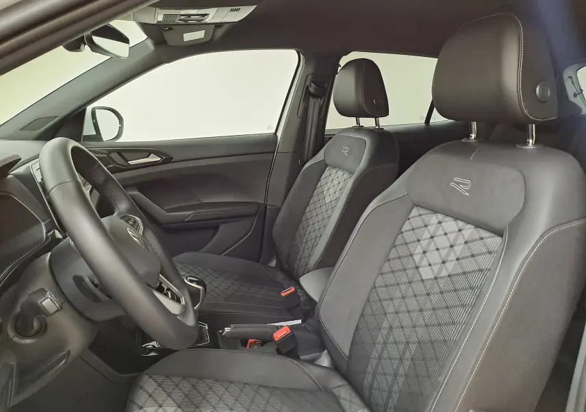 Intérieur du Volkswagen T-Cross 2025 R-Line Edition, vue côté gauche sur sièges noirs avec surpiqûres et logo R brodé.