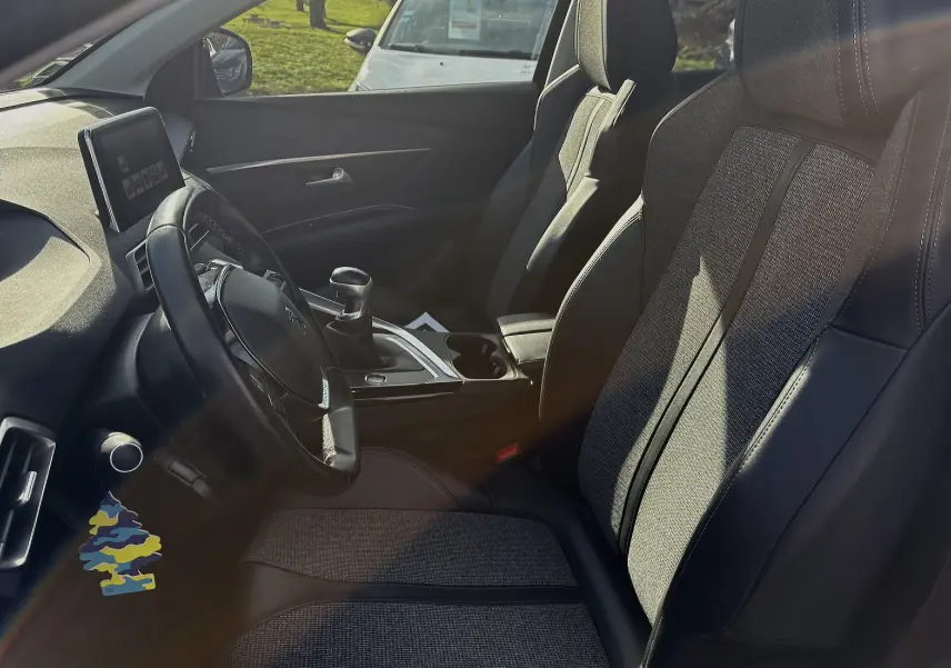 Intérieur du Peugeot 3008 II 2019, vue côté conducteur, sièges tissu et cuir gris, volant multifonction et écran tactile.