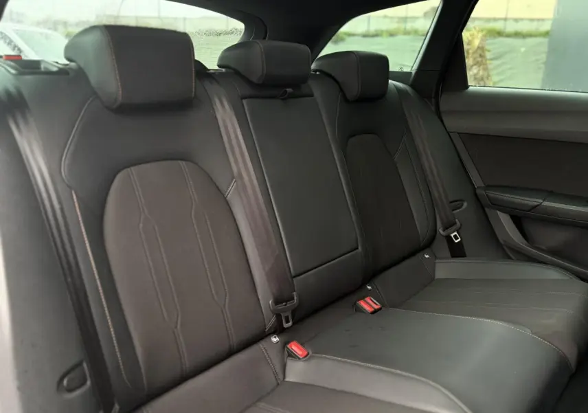 Vue intérieure des sièges arrière noirs du CUPRA LEON ST 2025, avec surpiqûres contrastantes et ceinture de sécurité visible.