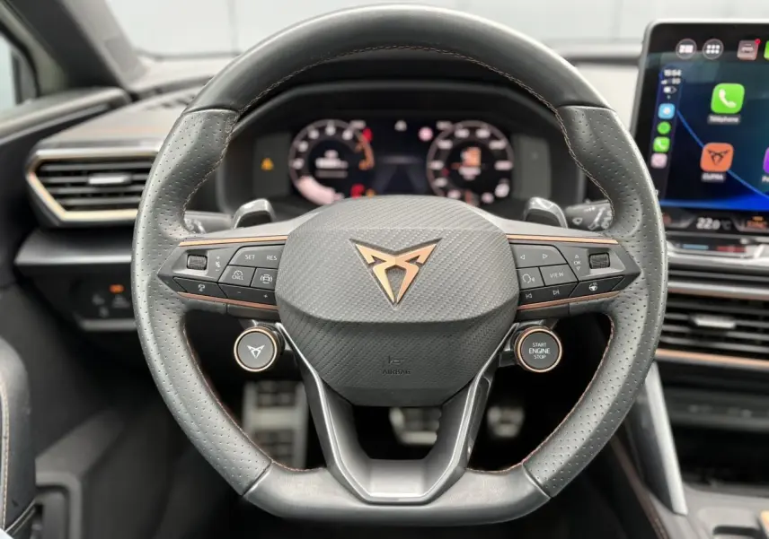Vue rapprochée du volant cuir perforé noir avec logo CUPRA cuivré et commandes intégrées du CUPRA LEON ST 2025.
