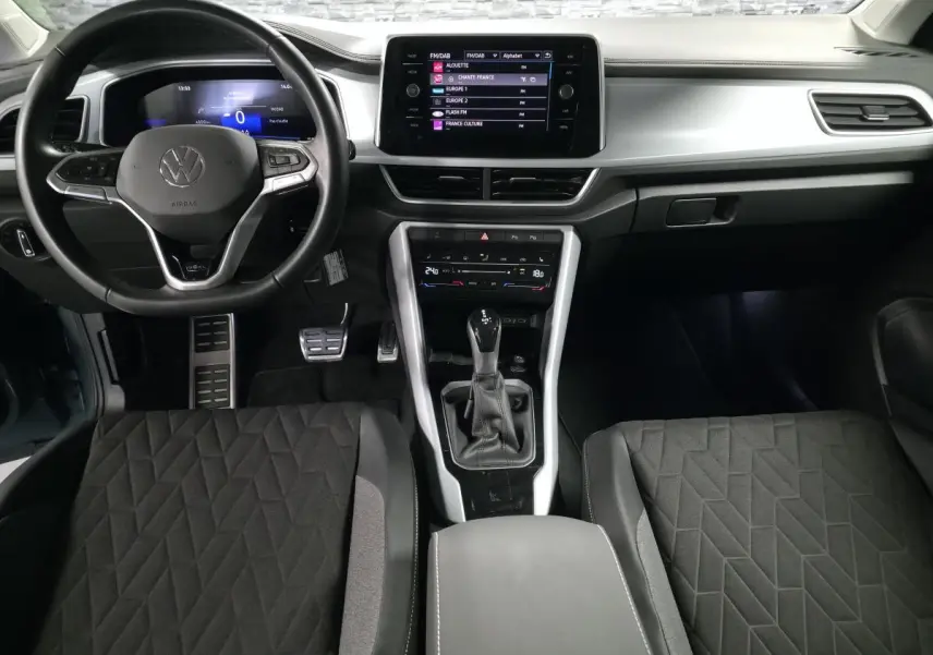 Vue intérieure frontale du Volkswagen T-Roc 2025 avec tableau de bord gris étain et écran tactile central.