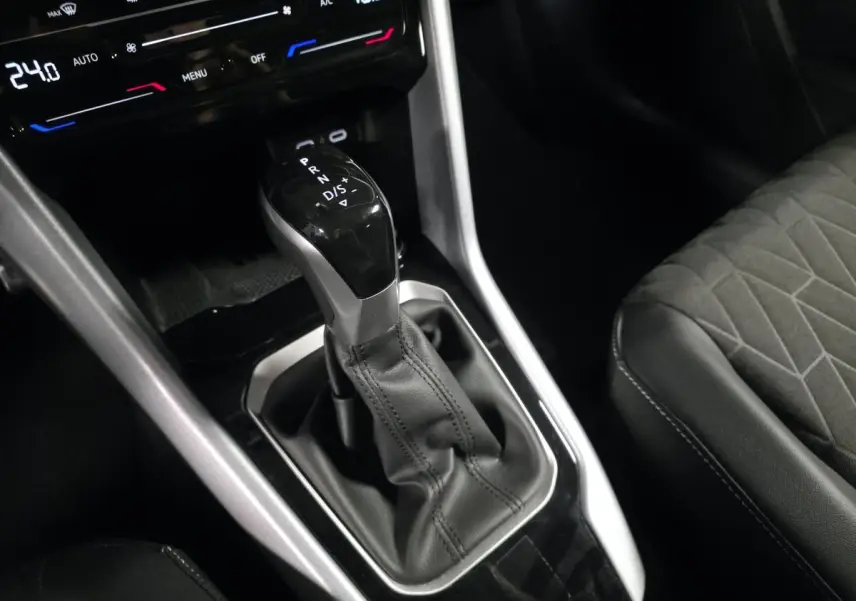 Gros plan sur le levier de vitesse automatique noir et argenté du Volkswagen T-Roc 2025 avec sellerie tissu gris.