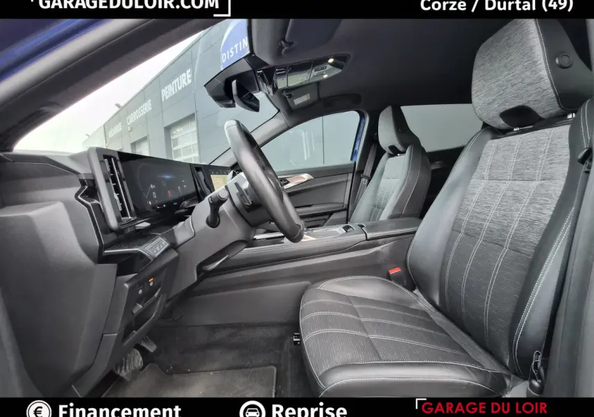 Vue intérieure côté conducteur du Renault Austral 2023 avec sièges tissu et cuir gris, volant multifonctions et tableau de bord numérique.