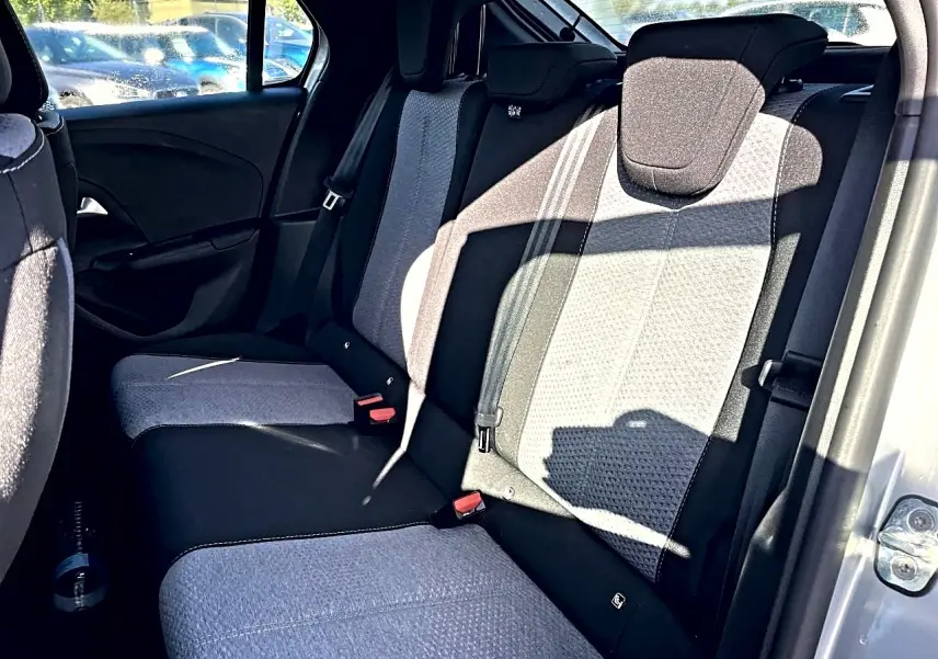 Vue côté droit de la banquette arrière bicolore gris et noir de l’Opel Corsa 2025 avec appuie-têtes et ceintures visibles.