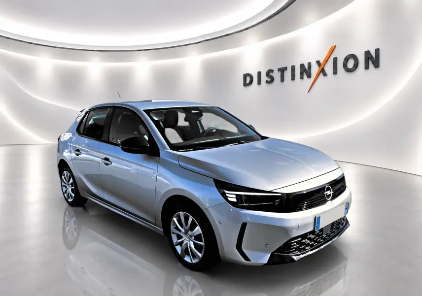Opel Corsa gris en 3/4 avant droit dans un showroom lumineux avec calandre noire et jantes alliage.