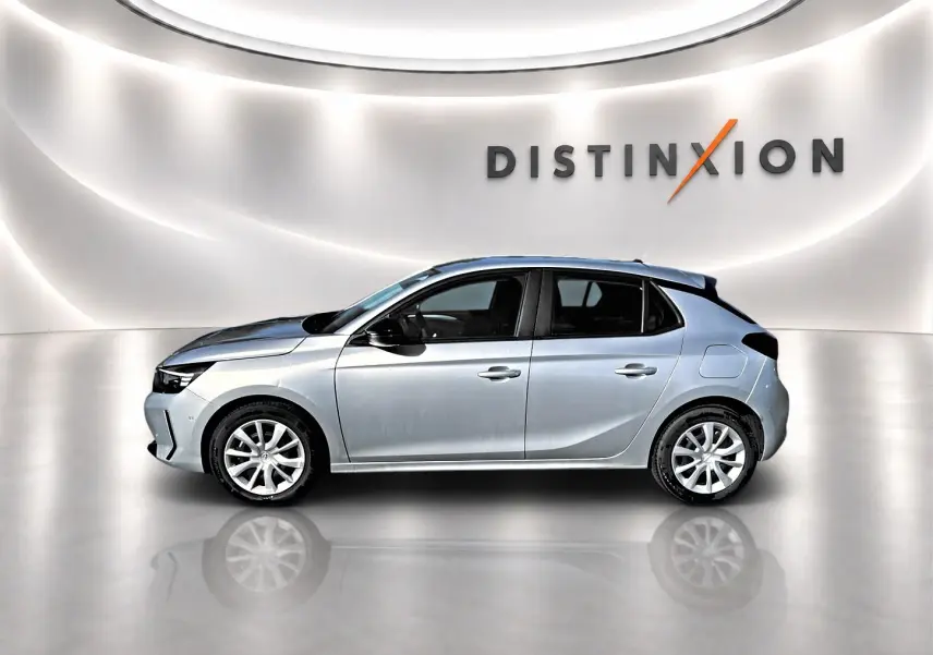 Vue de profil côté gauche d'une Opel Corsa gris métallisé 2025 dans un studio lumineux avec logo Distinxion en arrière-plan.
