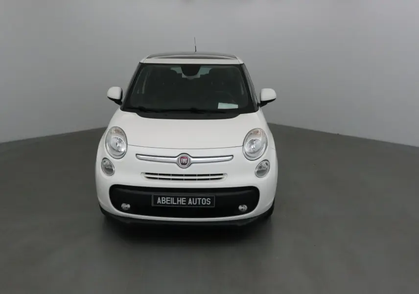 Vue de face d'une Fiat 500L blanche avec calandre chromée et plaque "ABEILHE AUTOS" sur fond neutre.