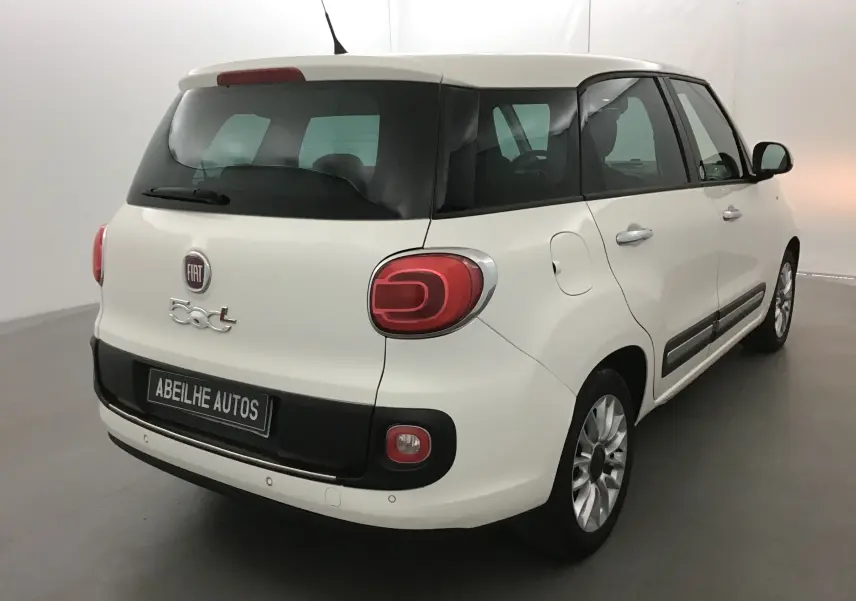 Vue 3/4 arrière droite d'une Fiat 500L blanche avec lunette arrière surteintée et feux arrière caractéristiques.