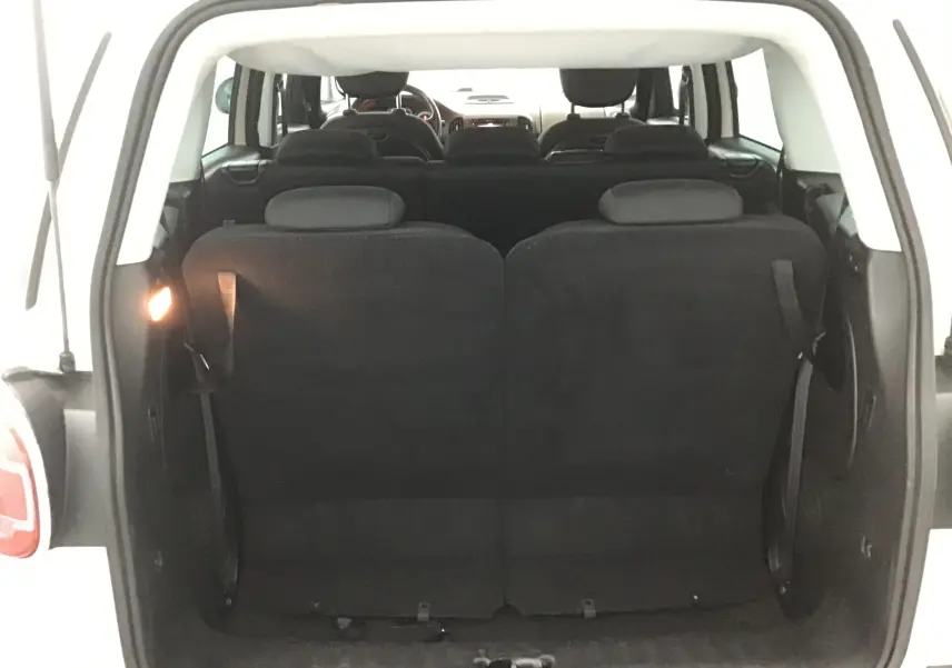 Vue arrière du coffre ouvert d'une FIAT 500L blanche, montrant les sièges arrière en position verticale et la lunette arrière surteintée.