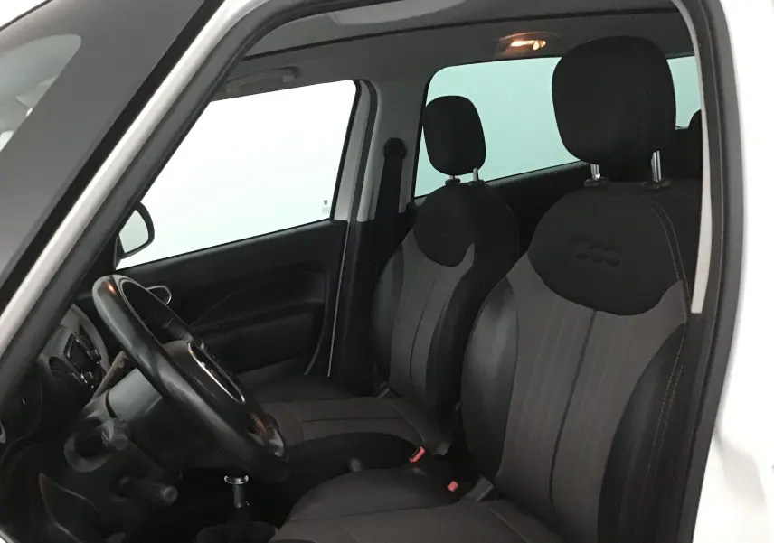 Intérieur de la FIAT 500L blanche vue côté conducteur, avec sièges noirs marqués du logo 500 et volant visible.