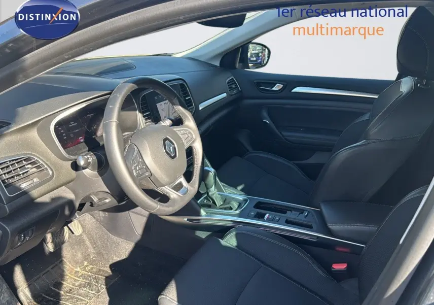 Intérieur avant de la Renault Mégane Break 2024 gris titanium, sièges noirs et tableau de bord moderne avec volant multifonction.