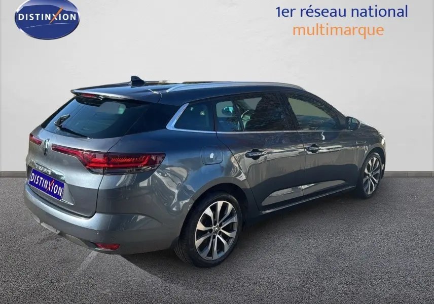 Vue 3/4 arrière droite d'une Renault Mégane Break gris titanium métal avec jantes alliage bicolores.