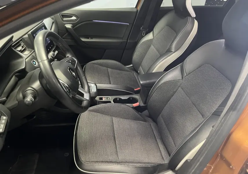 Vue intérieure côté conducteur du Renault Captur orange 2022, sièges tissu et cuir gris avec console centrale noire.