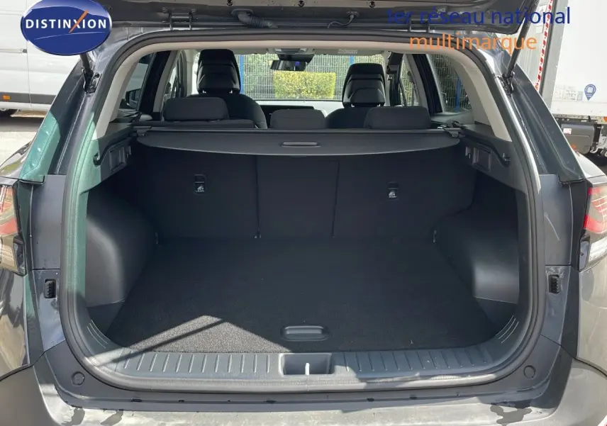 Coffre ouvert d'un Kia Sportage gris foncé 2025, vue arrière montrant l'espace de chargement et les sièges arrière.
