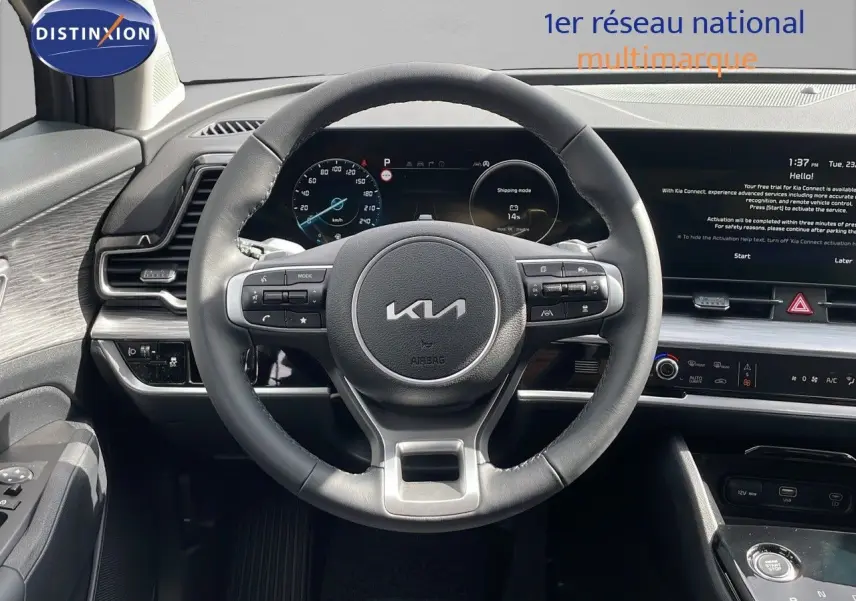 Vue intérieure centrée sur le volant cuir du Kia Sportage gris foncé 2025 avec tableau de bord digital et écran tactile.
