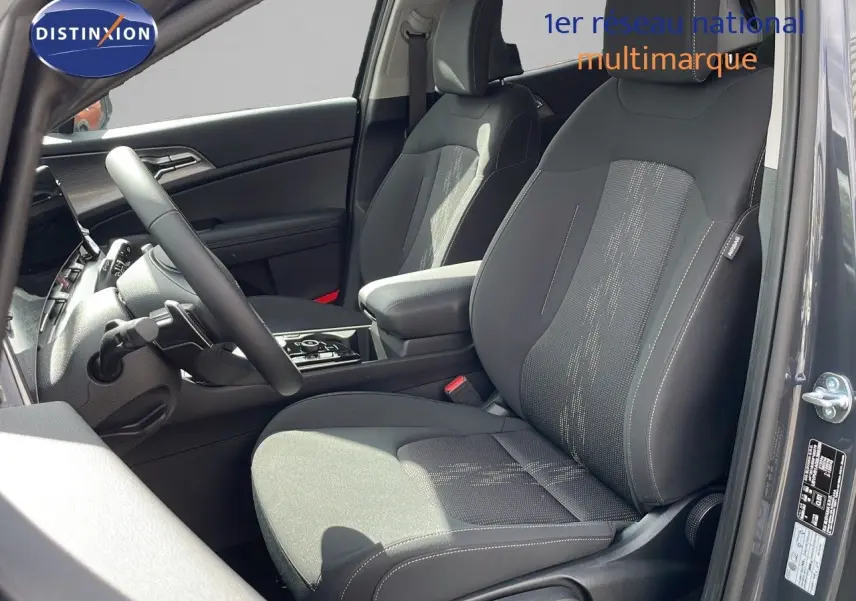 Intérieur du KIA SPORTAGE 2025 gris foncé, vue côté gauche sur les sièges avant en tissu noir avec console centrale.