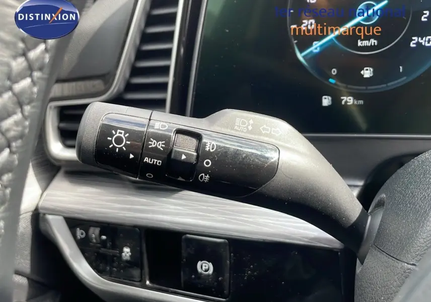 Gros plan sur la manette des feux et clignotants côté gauche du volant du KIA Sportage gris foncé 2025 avec tableau de bord digital.