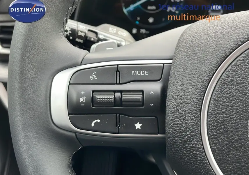 Gros plan sur les commandes multifonctions à gauche du volant en cuir noir du Kia Sportage gris foncé 2025.