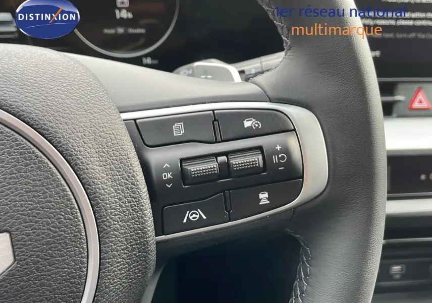 Gros plan sur les commandes au volant en cuir noir du Kia Sportage gris foncé 2025, mettant en valeur les boutons multifonctions.
