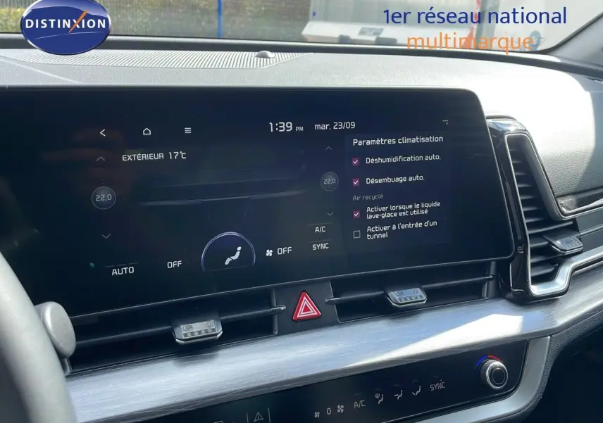 Tableau de bord du Kia Sportage 2025 gris foncé, vue rapprochée sur l'écran tactile et commandes de climatisation.