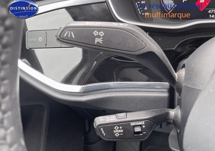 Gros plan sur les commandes au volant de l'Audi Q3 35 TFSI 2019, mettant en valeur les fonctions de régulateur et feux.