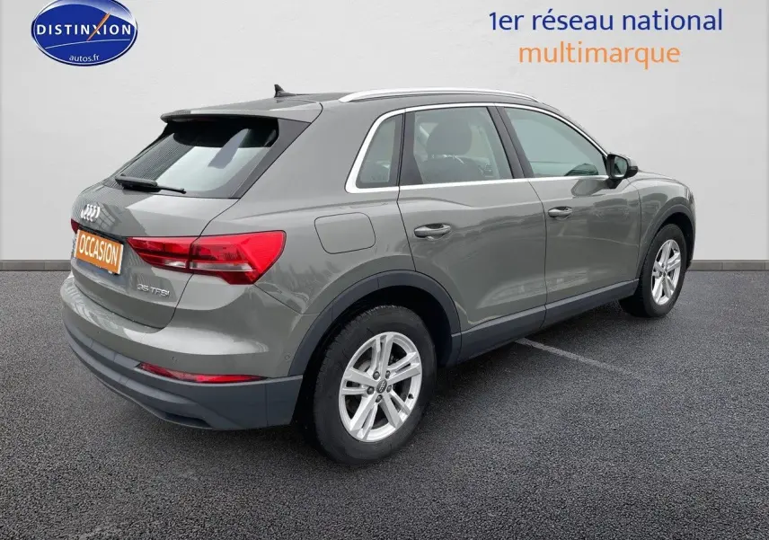 Audi Q3 gris Chronos métal vu en 3/4 arrière droit, soulignant ses feux arrière et jantes alliage.