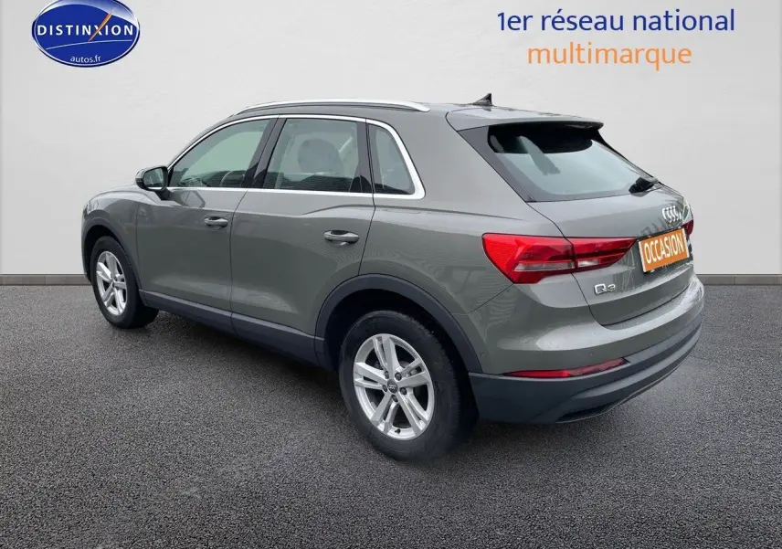 Audi Q3 gris Chronos métal vu de trois quarts arrière droit, mettant en valeur ses feux arrière et jantes alliage.