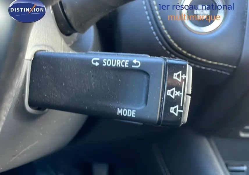 Gros plan sur la commande au volant noire avec fonctions source et mode du Renault Symbioz bleu Iron Metal, intérieur cuir noir.