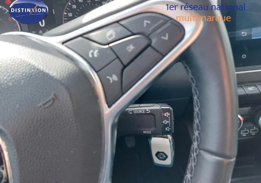 Vue rapprochée du volant de la Renault Clio blanche 2021, avec commandes audio intégrées et tableau de bord partiel.