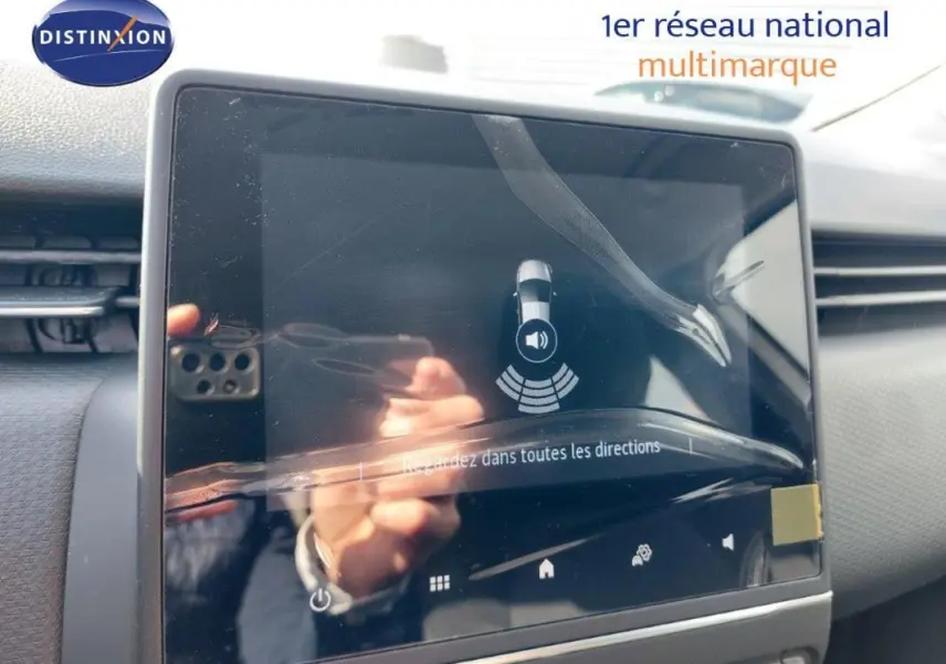 Écran tactile central du tableau de bord de la Renault Clio blanche 2021, affichant l'aide au stationnement.