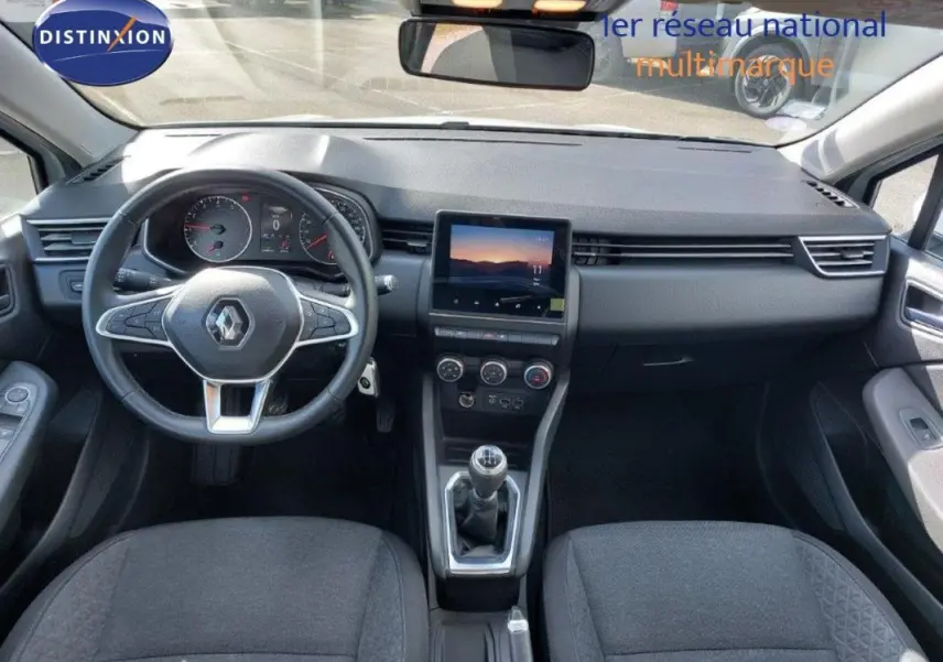 Vue intérieure avant de la Renault Clio blanche 2021, tableau de bord avec écran tactile et boîte manuelle visible.