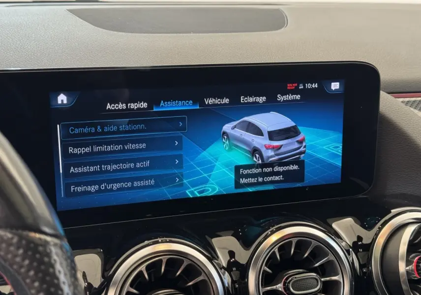 Écran tactile intérieur montrant l'assistance au stationnement avec une vue 3D du Mercedes GLA gris côté arrière droit.