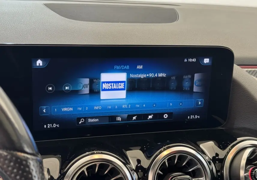 Vue intérieure centrée sur l'écran tactile multimédia et les aérateurs ronds chromés du tableau de bord noir.