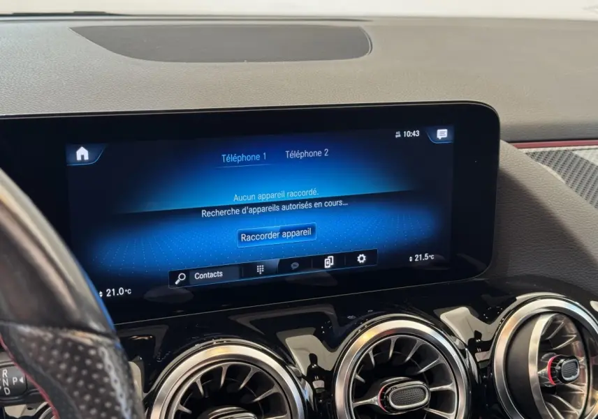 Vue intérieure du tableau de bord noir du Mercedes GLA 250 e AMG Line 2021, avec écran tactile central et aérateurs ronds chromés.