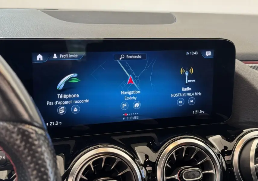 Vue rapprochée de l’écran tactile central et des aérateurs ronds chromés du tableau de bord du Mercedes GLA noir.