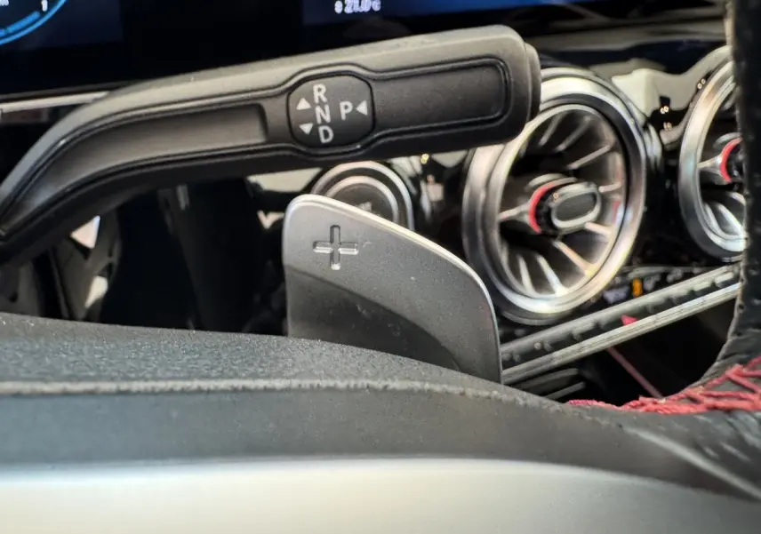 Gros plan sur la palette de changement de vitesse droite et commandes autour du volant d’un Mercedes GLA 250 e AMG Line noir.