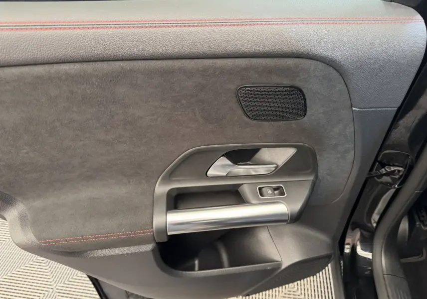Détail de la porte avant droite noire du Mercedes GLA 250 e AMG Line 2021 avec poignée alu et surpiqûres rouges.