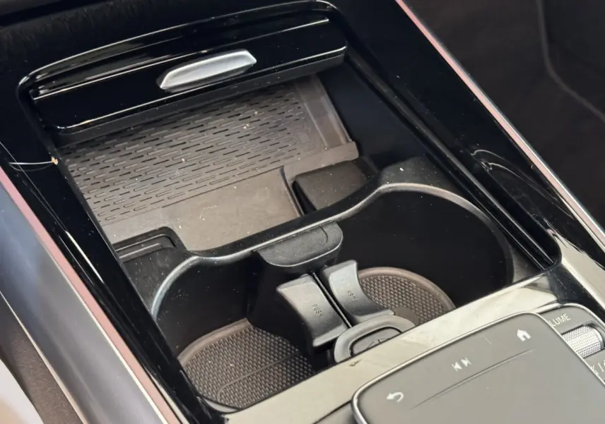Gros plan sur la console centrale noire du Mercedes GLA 250 e AMG Line, avec porte-gobelets et pavé tactile de commande.