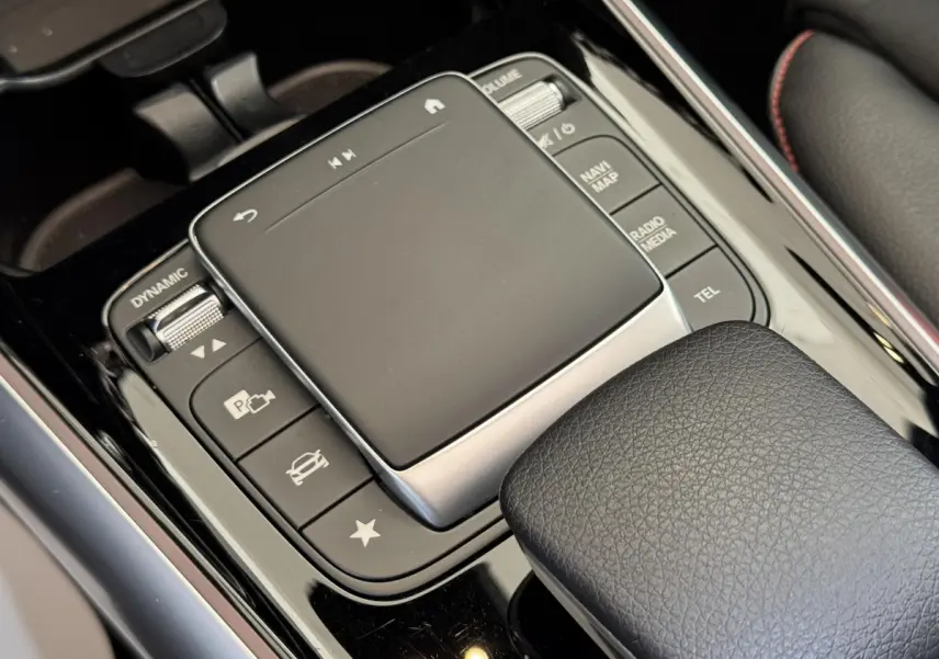 Gros plan sur le pavé tactile central et commandes noires du Mercedes GLA 250 e AMG Line, intérieur cuir noir.