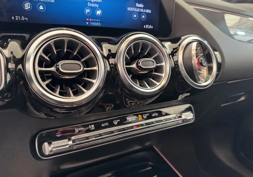 Détail intérieur du tableau de bord noir du Mercedes GLA 250 e AMG Line 2021, avec aérateurs ronds et écran tactile.