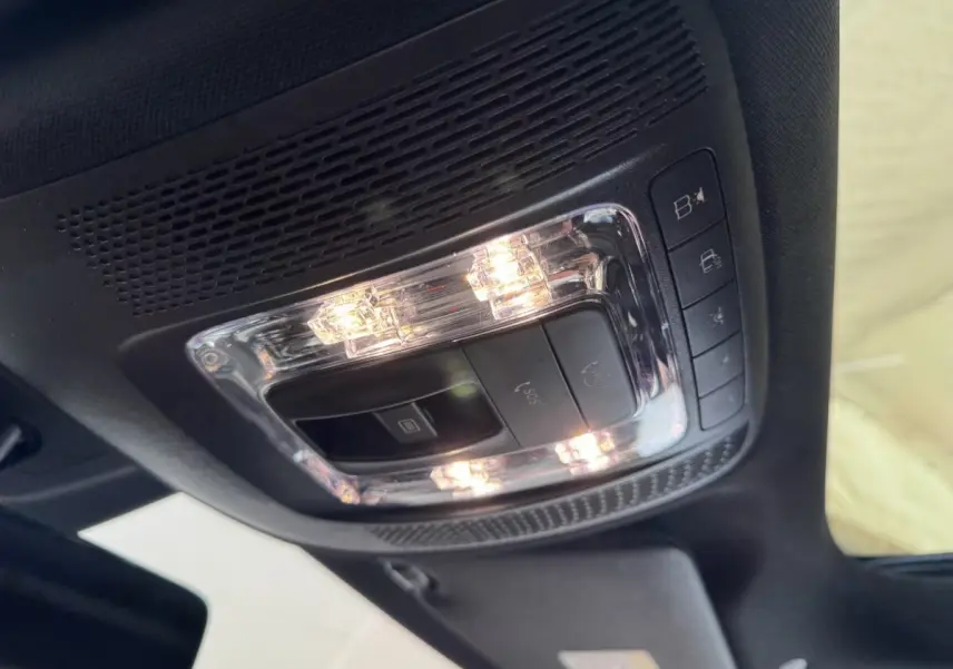 Plafonnier intérieur allumé avec commandes SOS et éclairage, vue du toit d’un Mercedes GLA 250 e AMG Line noir.