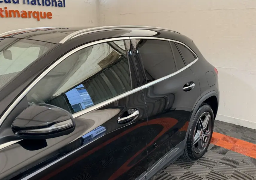 Vue latérale gauche d'un Mercedes GLA 250 e AMG Line noir brillant avec jantes étoile et rétroviseur électrique.