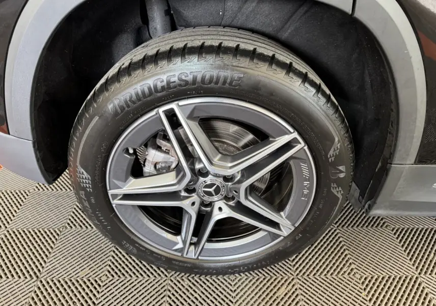 Gros plan sur la roue avant droite noire d'une Mercedes GLA 250 e AMG Line avec jante AMG à cinq branches.